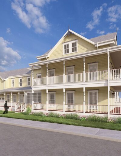 A two-story yellow house with a wraparound porch and white trim, situated on a residential street, with several people standing and walking around it on a clear day.