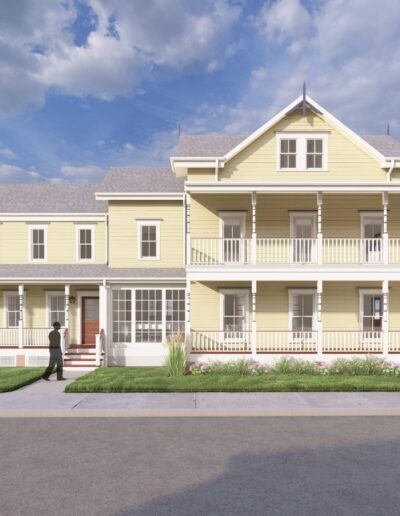 A large yellow house with a wraparound porch, multiple gables, and a garage. A person stands on the sidewalk in front of the house. The sky is partly cloudy.