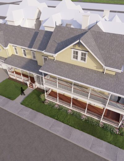 Aerial view of two identical two-story houses with beige exteriors and large front porches, situated on a corner lot with sidewalks and sparse landscaping.